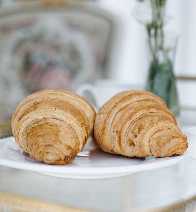 Two butter croissants on a white plate at breakfast
