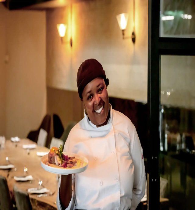 A chef carrying a plated dinner dish through the restaurant