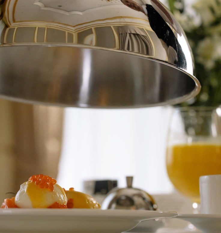 A room service tray with a cloche being lifted